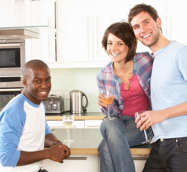 Group Of Young Friends Enjoying Glass Of Wine In Modern Kitchen