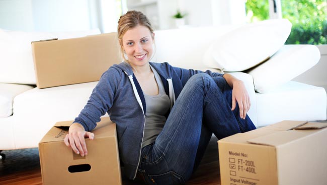 Young girl sitting by cardboards in new home